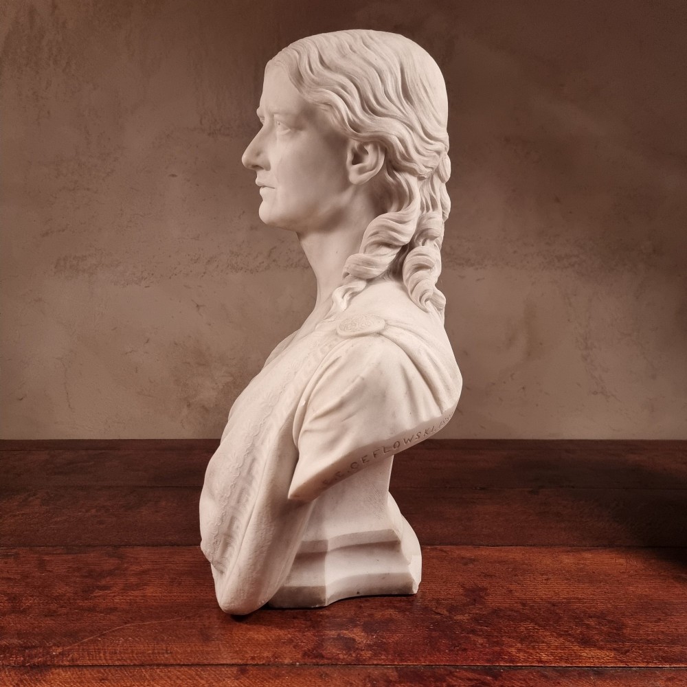 A pair of carved white marble portrait busts depicting a classical female figure on the left and a bearded man in Victorian attire on the right. View XII