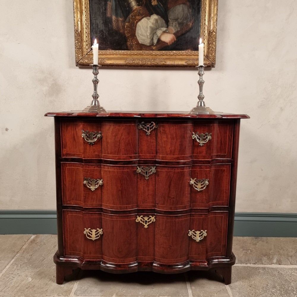 An 18th-century dark mahogany serpentine chest of drawers featuring three horizontal drawers with decorative brass handles.