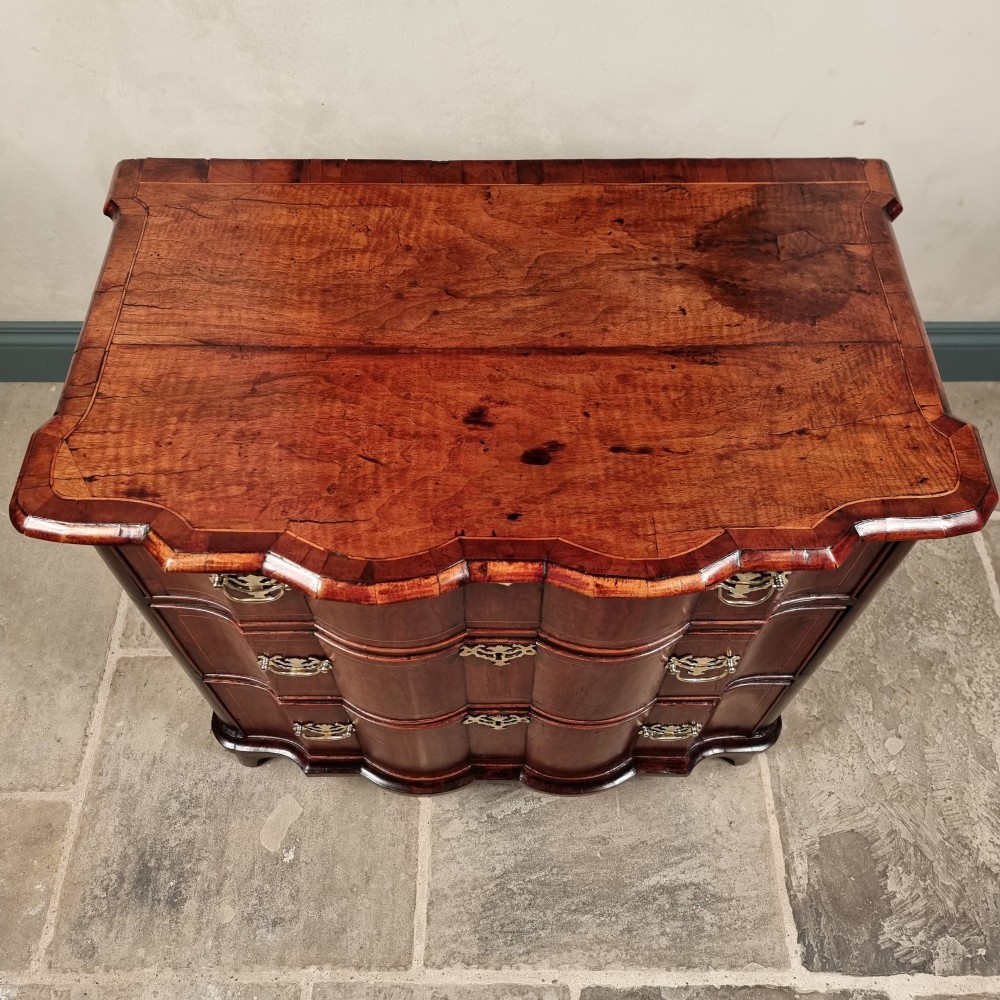An 18th-century dark mahogany serpentine chest of drawers featuring three horizontal drawers with decorative brass handles. View III