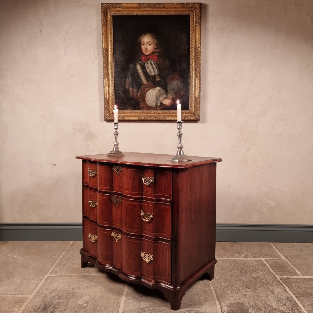 An 18th-century dark mahogany serpentine chest of drawers featuring three horizontal drawers with decorative brass handles. View VI