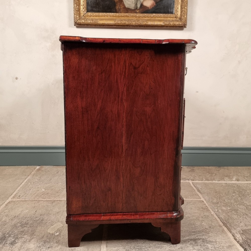 An 18th-century dark mahogany serpentine chest of drawers featuring three horizontal drawers with decorative brass handles. View IX