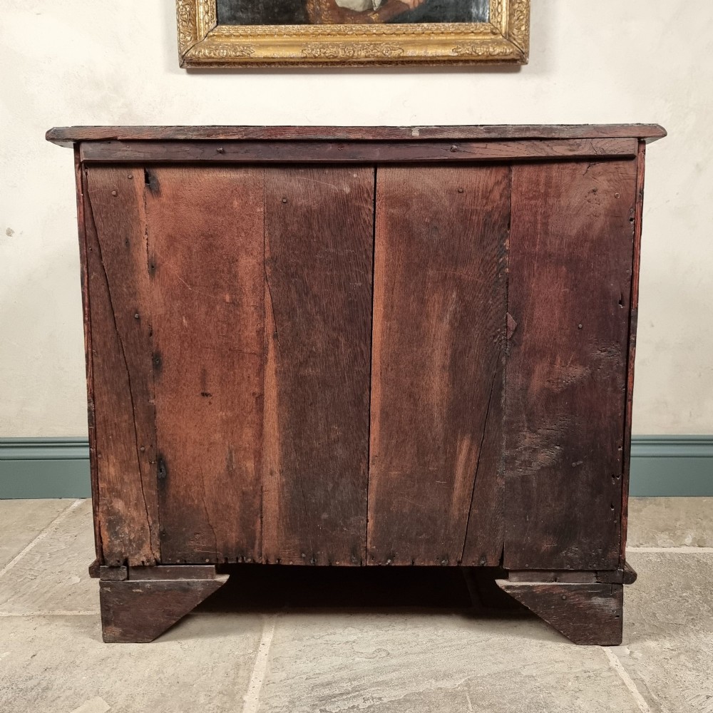An 18th-century dark mahogany serpentine chest of drawers featuring three horizontal drawers with decorative brass handles. View X