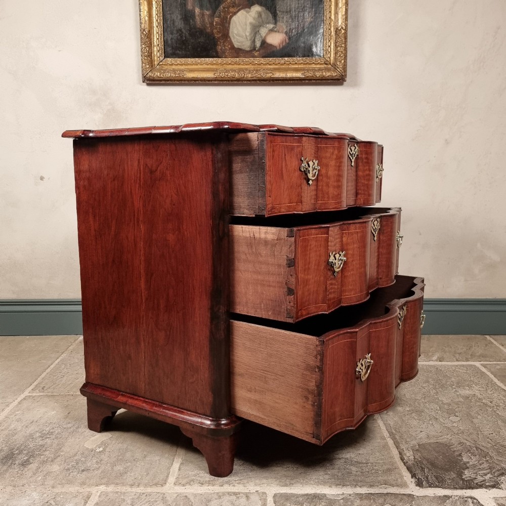 An 18th-century dark mahogany serpentine chest of drawers featuring three horizontal drawers with decorative brass handles. View XII