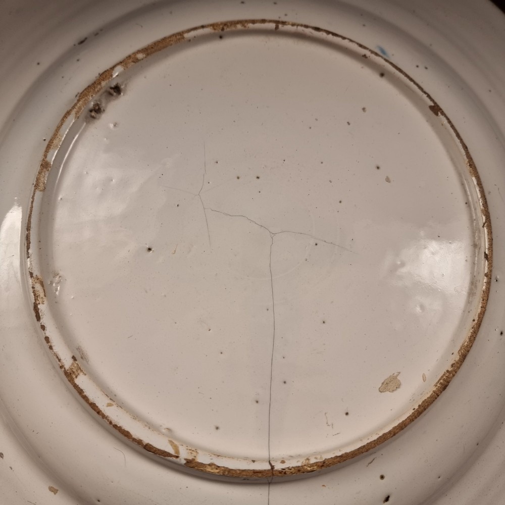 A circular 17th century tin-glazed earthenware Delft charger hand-painted with cobalt blue Chinoiserie figures and foliage against a creamy white ground. View VII