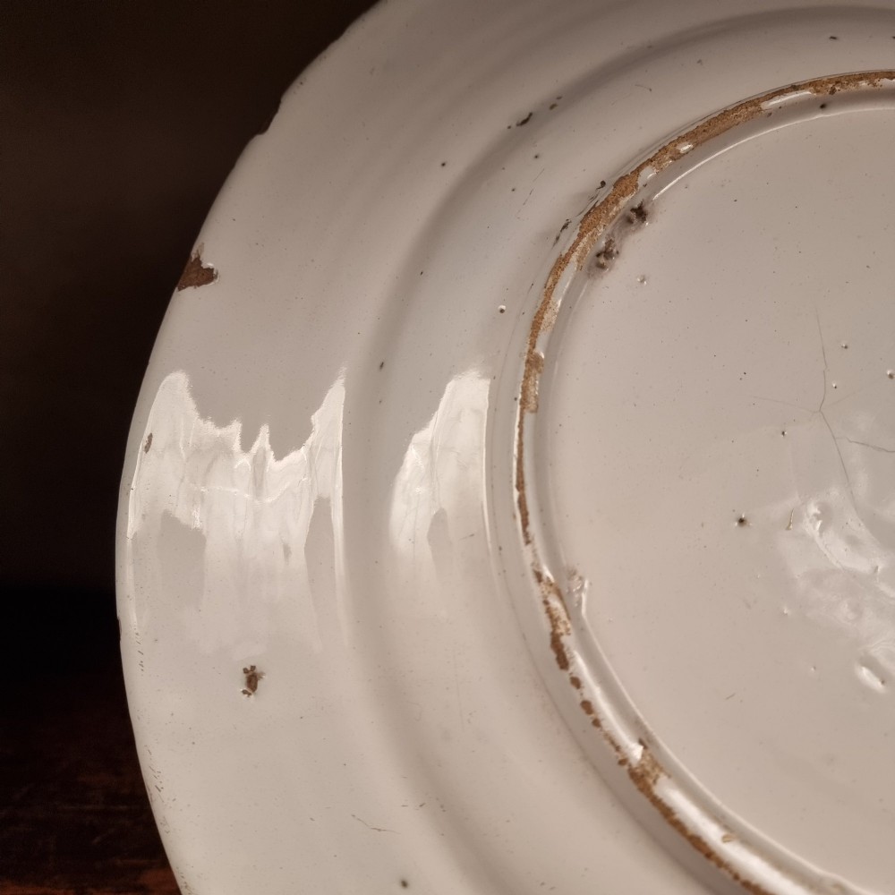 A circular 17th century tin-glazed earthenware Delft charger hand-painted with cobalt blue Chinoiserie figures and foliage against a creamy white ground. View VIII