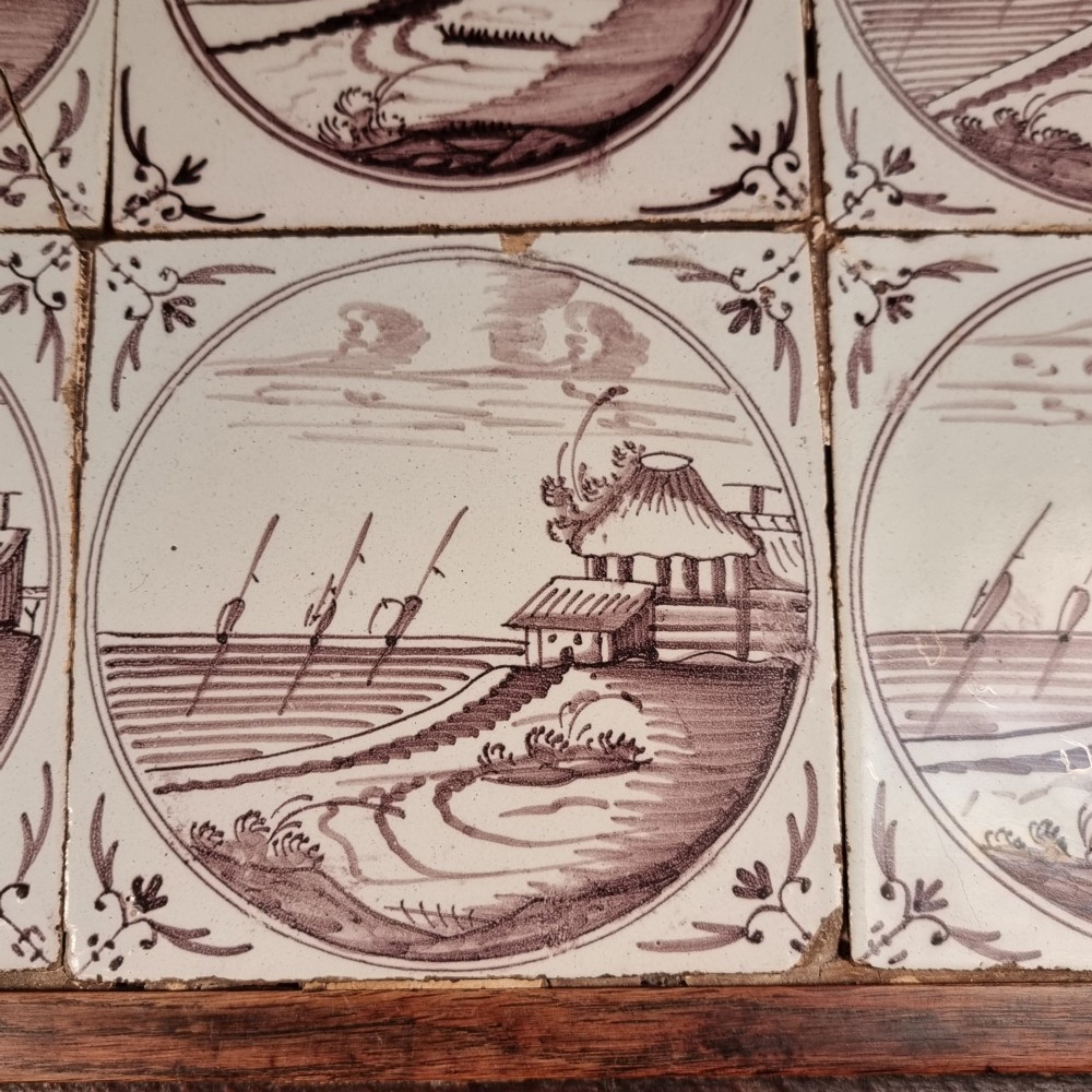 Ten eighteenth-century manganese delft tiles with hand-painted coastal landscapes set in circular reserves, mounted in two wooden frames. View IV