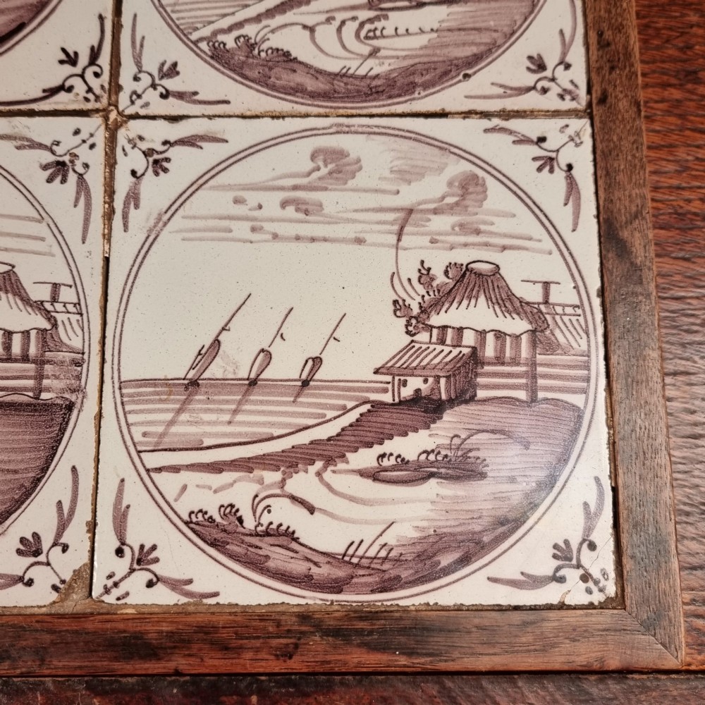 Ten eighteenth-century manganese delft tiles with hand-painted coastal landscapes set in circular reserves, mounted in two wooden frames. View V