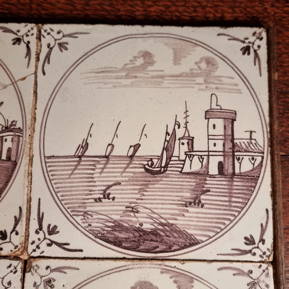 Ten eighteenth-century manganese delft tiles with hand-painted coastal landscapes set in circular reserves, mounted in two wooden frames. View X