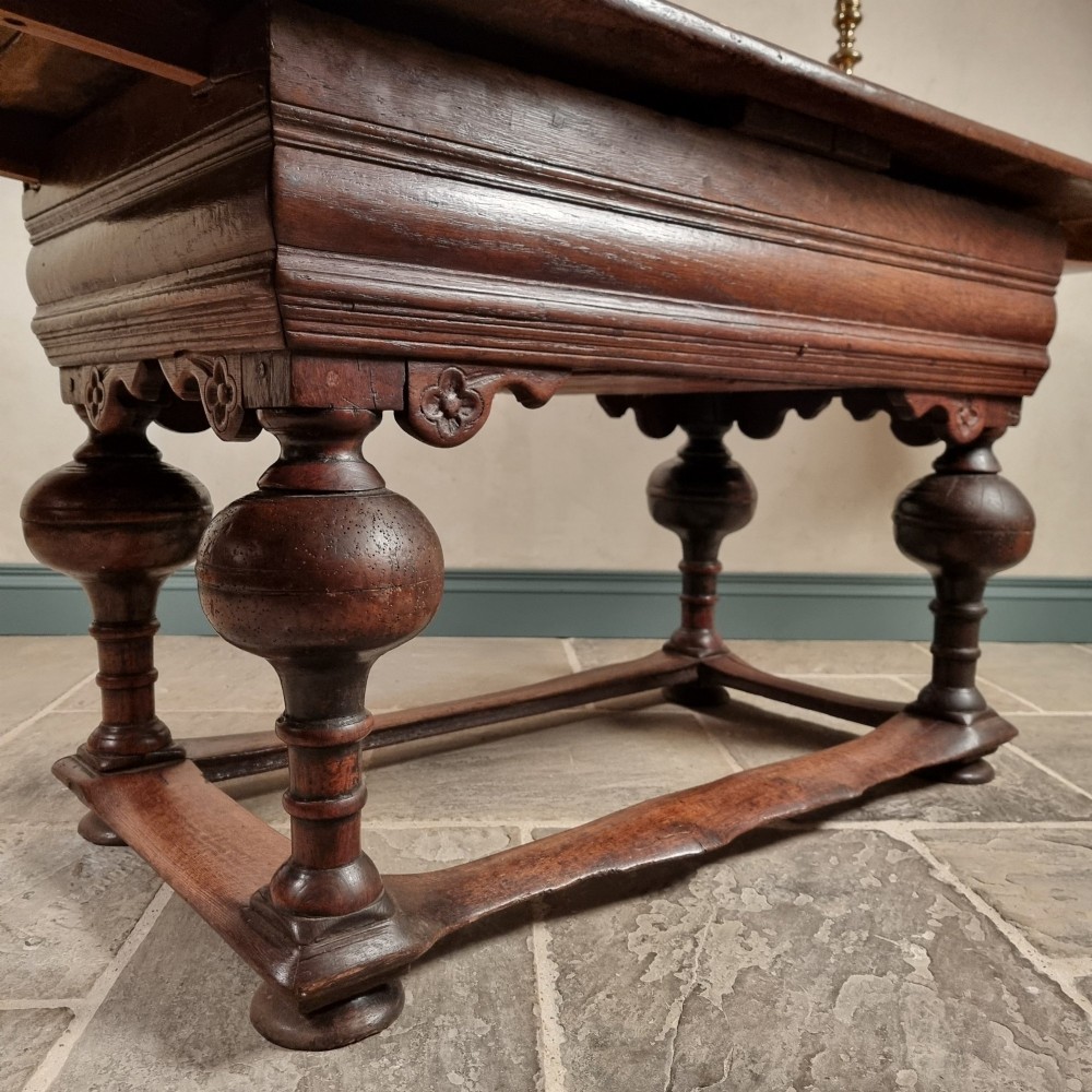 A dark oak seventeenth-century refectory dining table with extensible draw leaves, bulbous turned legs, and a floor-level perimeter stretcher. View II