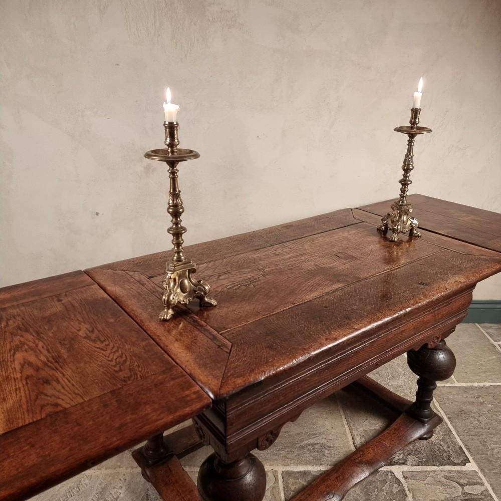 A dark oak seventeenth-century refectory dining table with extensible draw leaves, bulbous turned legs, and a floor-level perimeter stretcher. View IV