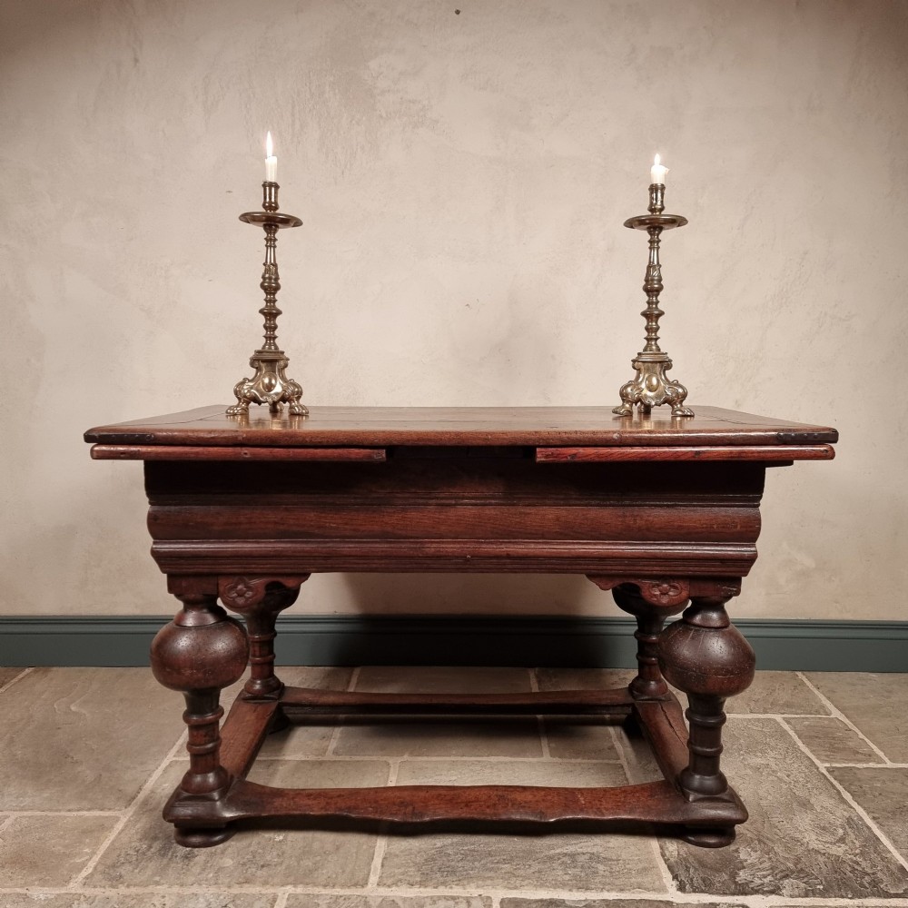A dark oak seventeenth-century refectory dining table with extensible draw leaves, bulbous turned legs, and a floor-level perimeter stretcher. View V