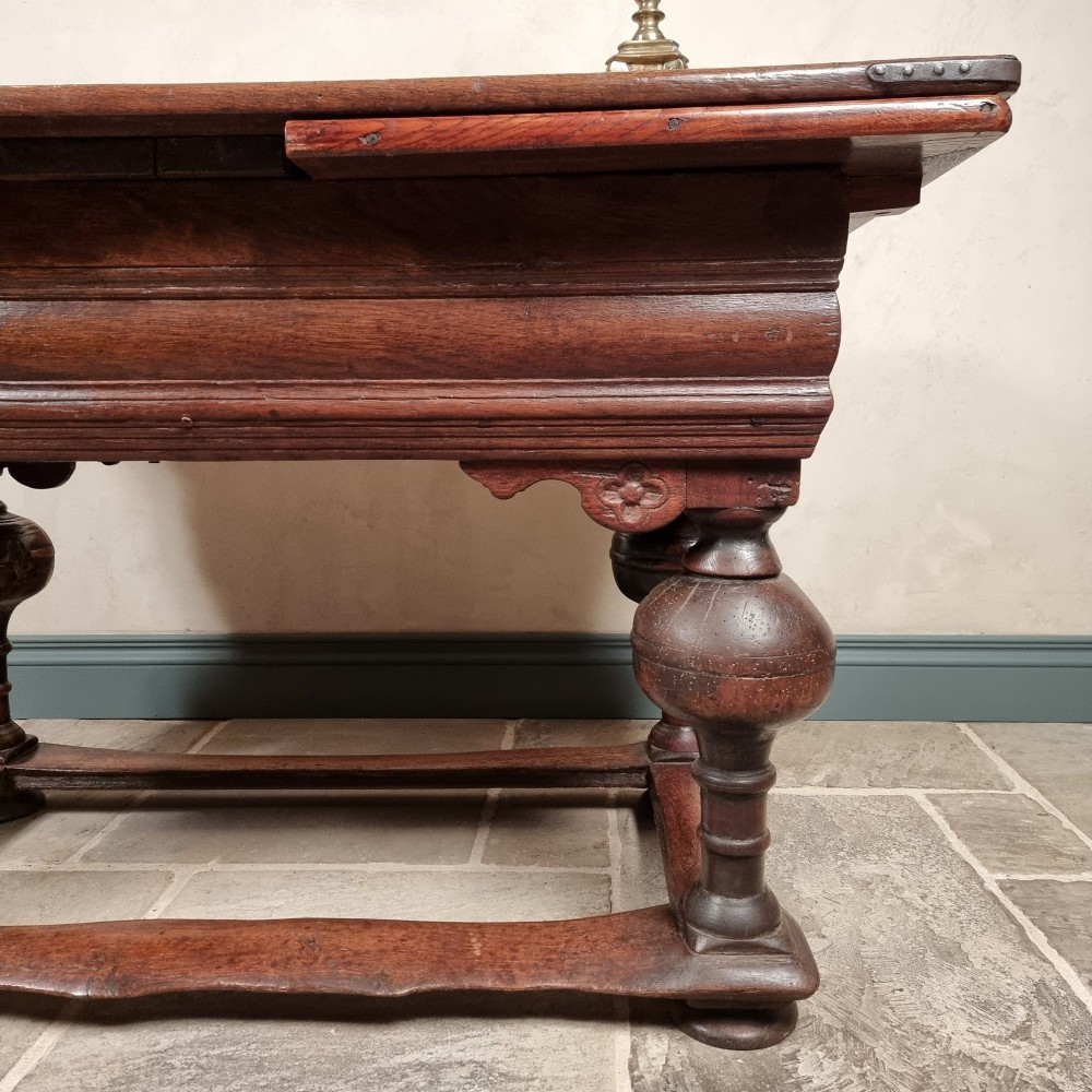 A dark oak seventeenth-century refectory dining table with extensible draw leaves, bulbous turned legs, and a floor-level perimeter stretcher. View VII