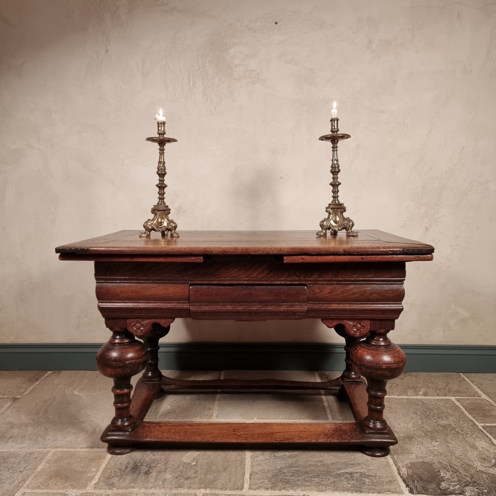 A dark oak seventeenth-century refectory dining table with extensible draw leaves, bulbous turned legs, and a floor-level perimeter stretcher. View IX