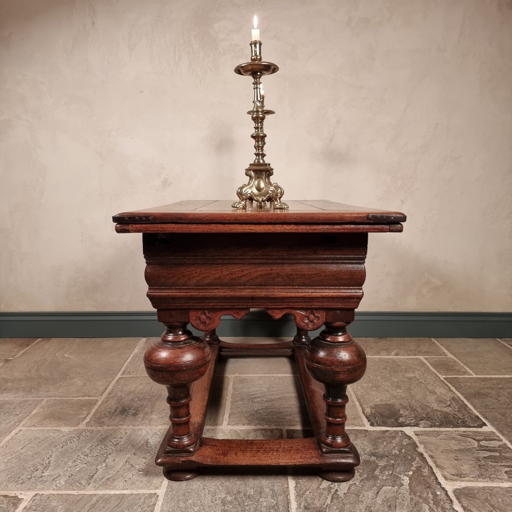 A dark oak seventeenth-century refectory dining table with extensible draw leaves, bulbous turned legs, and a floor-level perimeter stretcher. View X