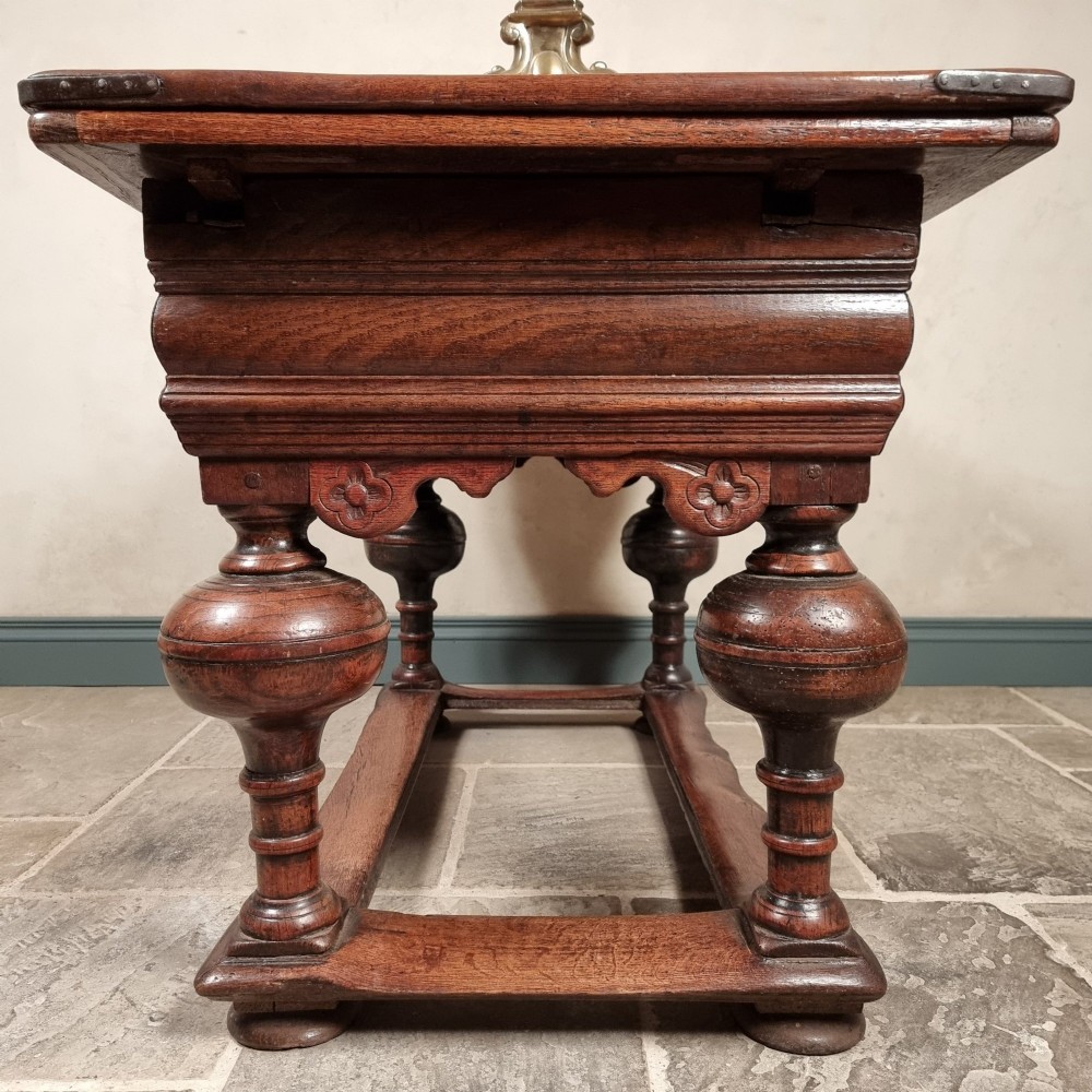 A dark oak seventeenth-century refectory dining table with extensible draw leaves, bulbous turned legs, and a floor-level perimeter stretcher. View XI