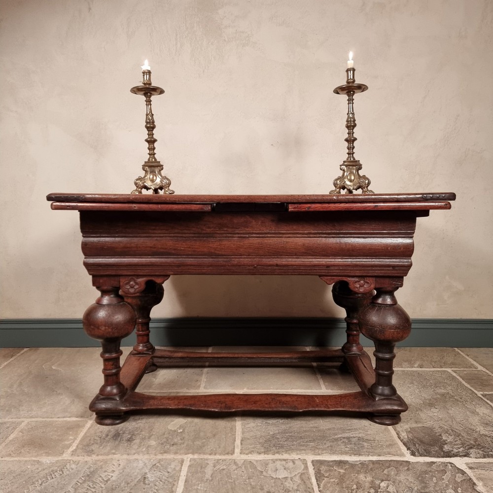 A dark oak seventeenth-century refectory dining table with extensible draw leaves, bulbous turned legs, and a floor-level perimeter stretcher. View XII