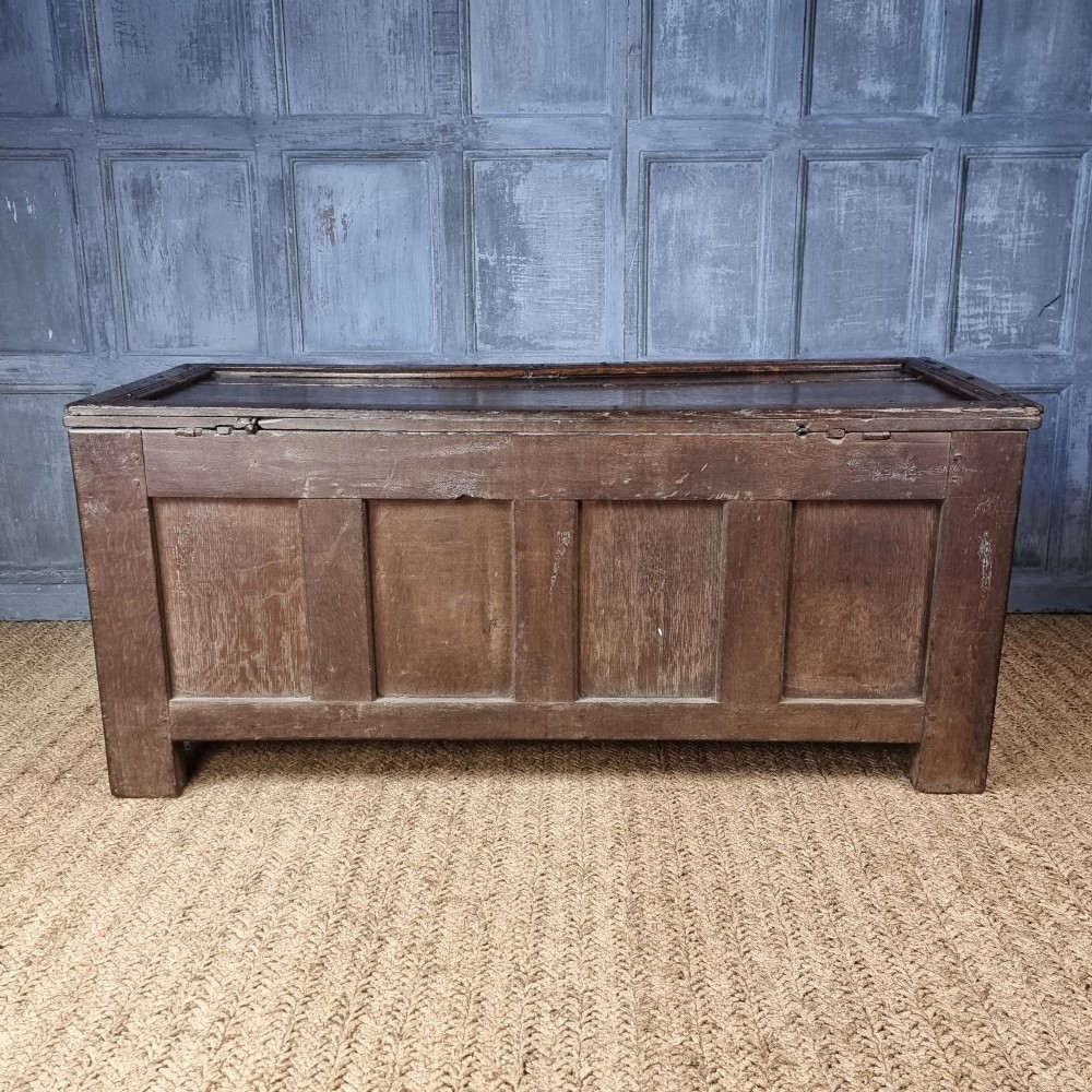 A late Elizabethan dark oak coffer with a rectangular hinged lid, iron lockplate, and panelled front facade. View IX