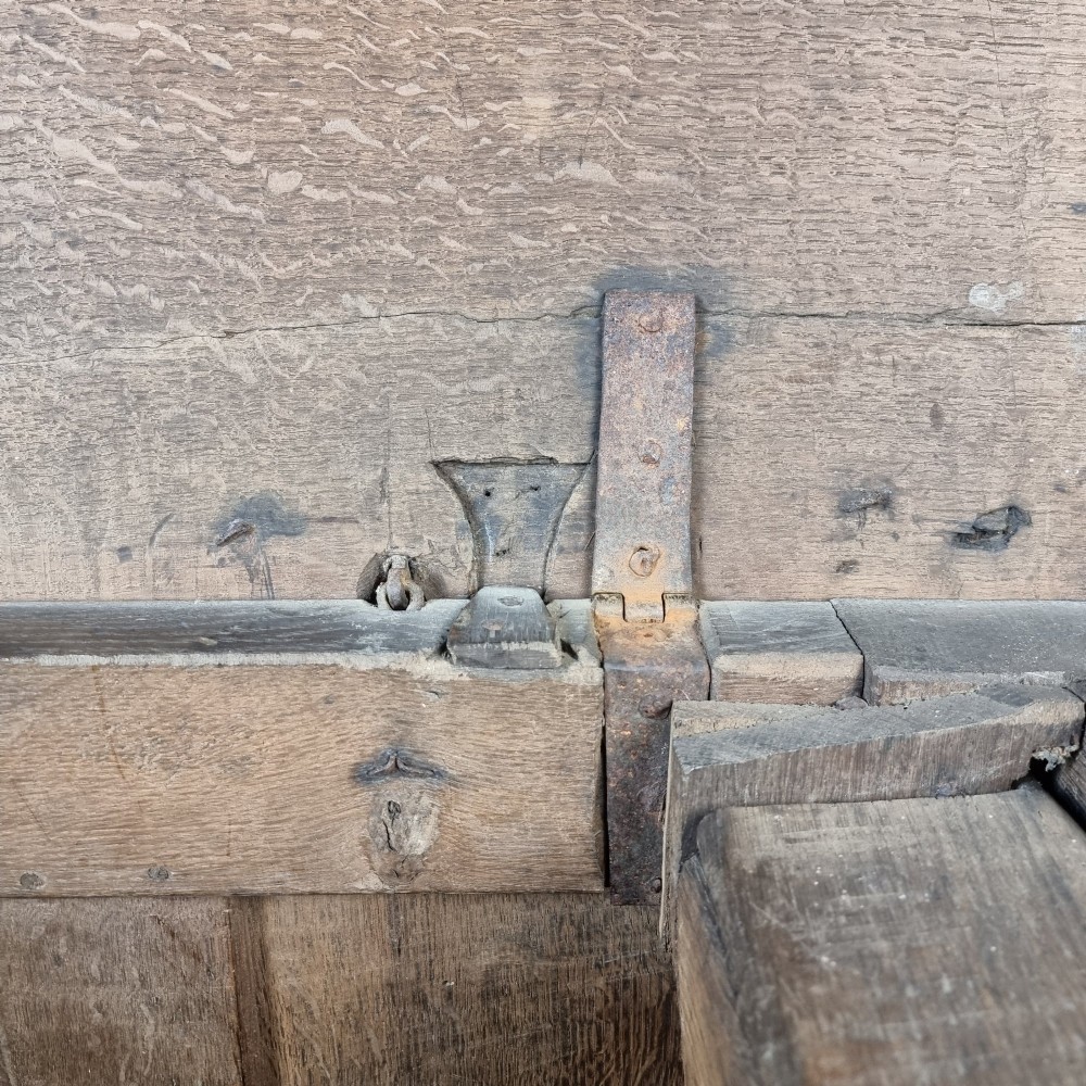 A late Elizabethan dark oak coffer with a rectangular hinged lid, iron lockplate, and panelled front facade. View XII