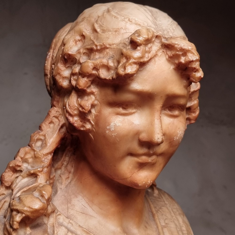 A 19th-century carved alabaster bust depicting a young woman with wavy hair and draped clothing mounted on a turned pedestal base. View III