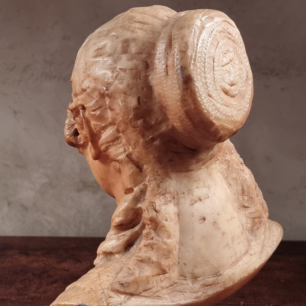 A 19th-century carved alabaster bust depicting a young woman with wavy hair and draped clothing mounted on a turned pedestal base. View VII