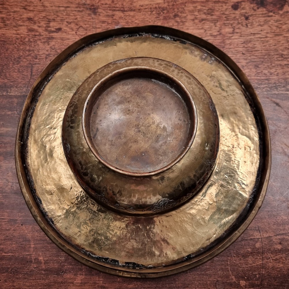 A circular 19th-century Islamic brass wash bowl featuring intricate Arabic calligraphic script, geometric arabesque patterns, pierced metalwork, and silver and copper inlay. View IV