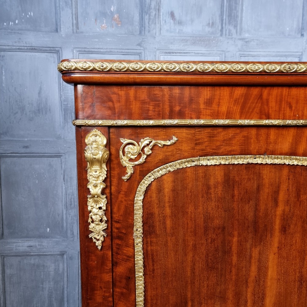 A 19th-century flame mahogany enclosed chest featuring twin doors framed with gilded metal moulding and corner mounts. View II