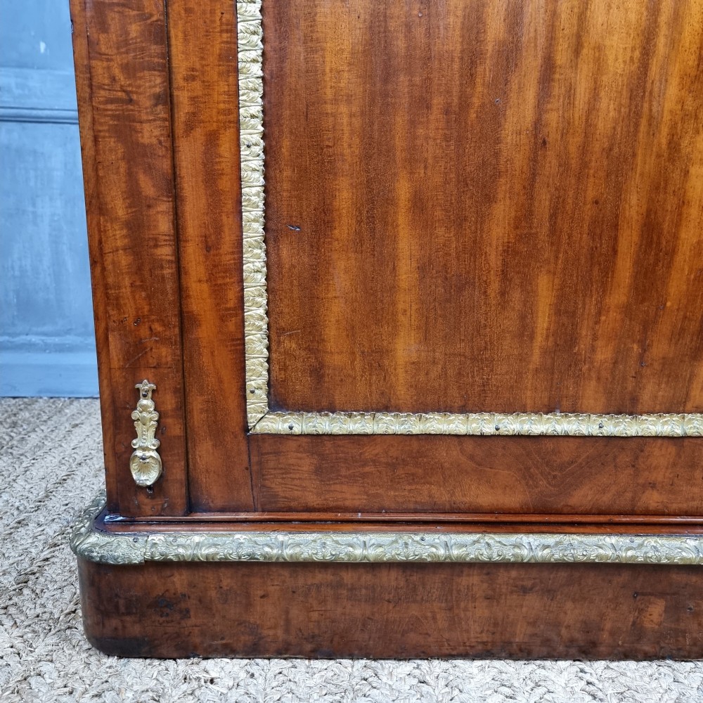 A 19th-century flame mahogany enclosed chest featuring twin doors framed with gilded metal moulding and corner mounts. View III