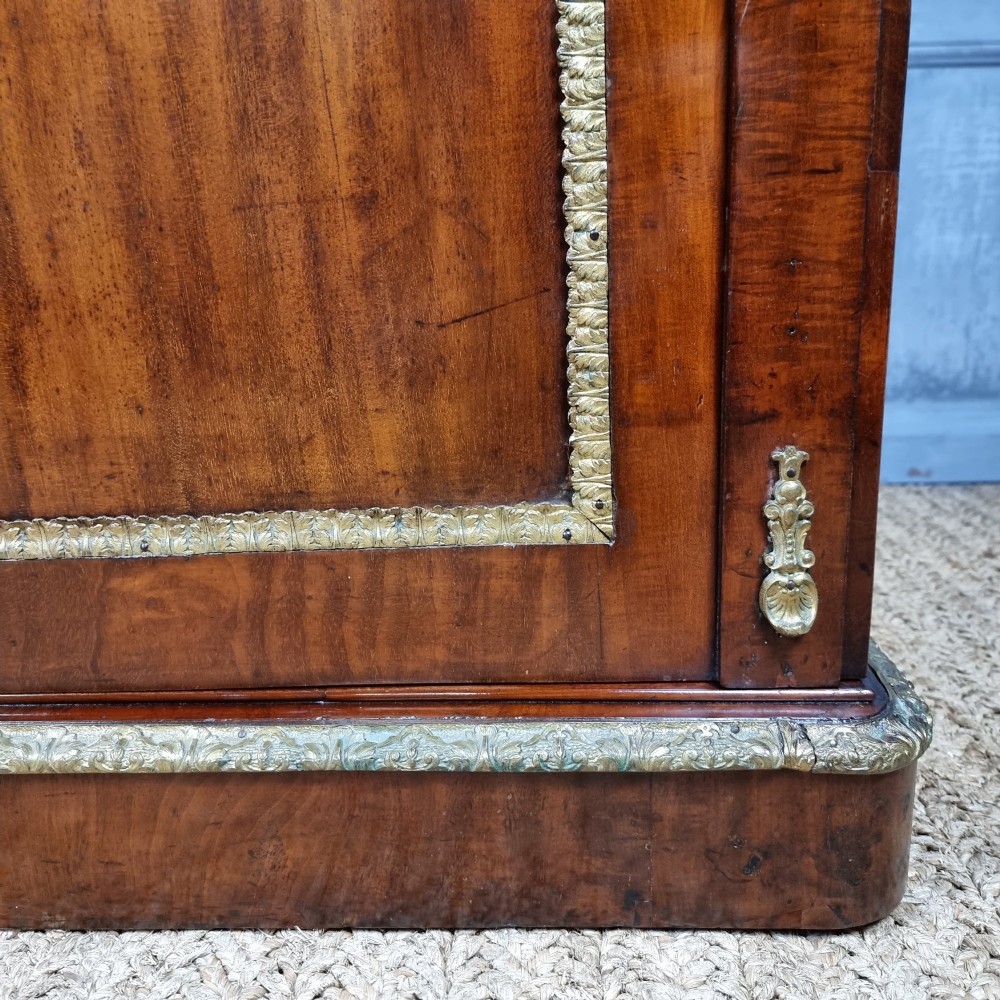 A 19th-century flame mahogany enclosed chest featuring twin doors framed with gilded metal moulding and corner mounts. View V