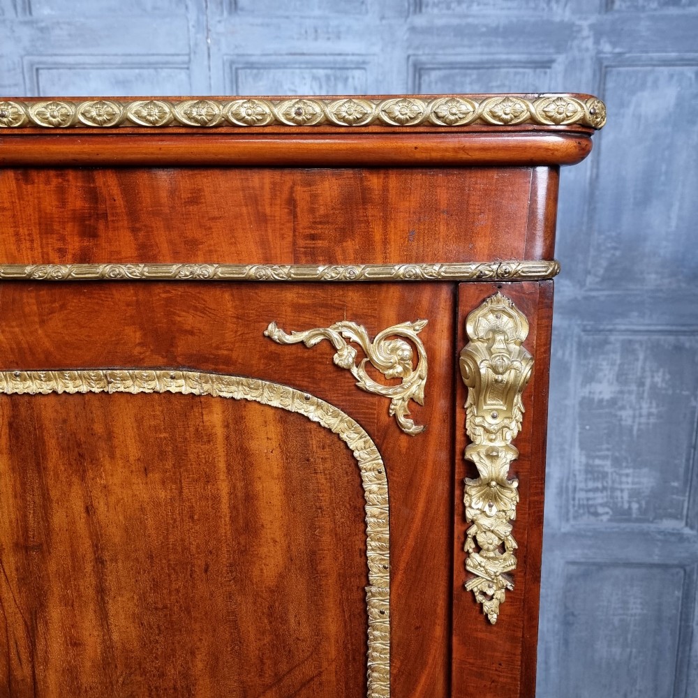 A 19th-century flame mahogany enclosed chest featuring twin doors framed with gilded metal moulding and corner mounts. View VI