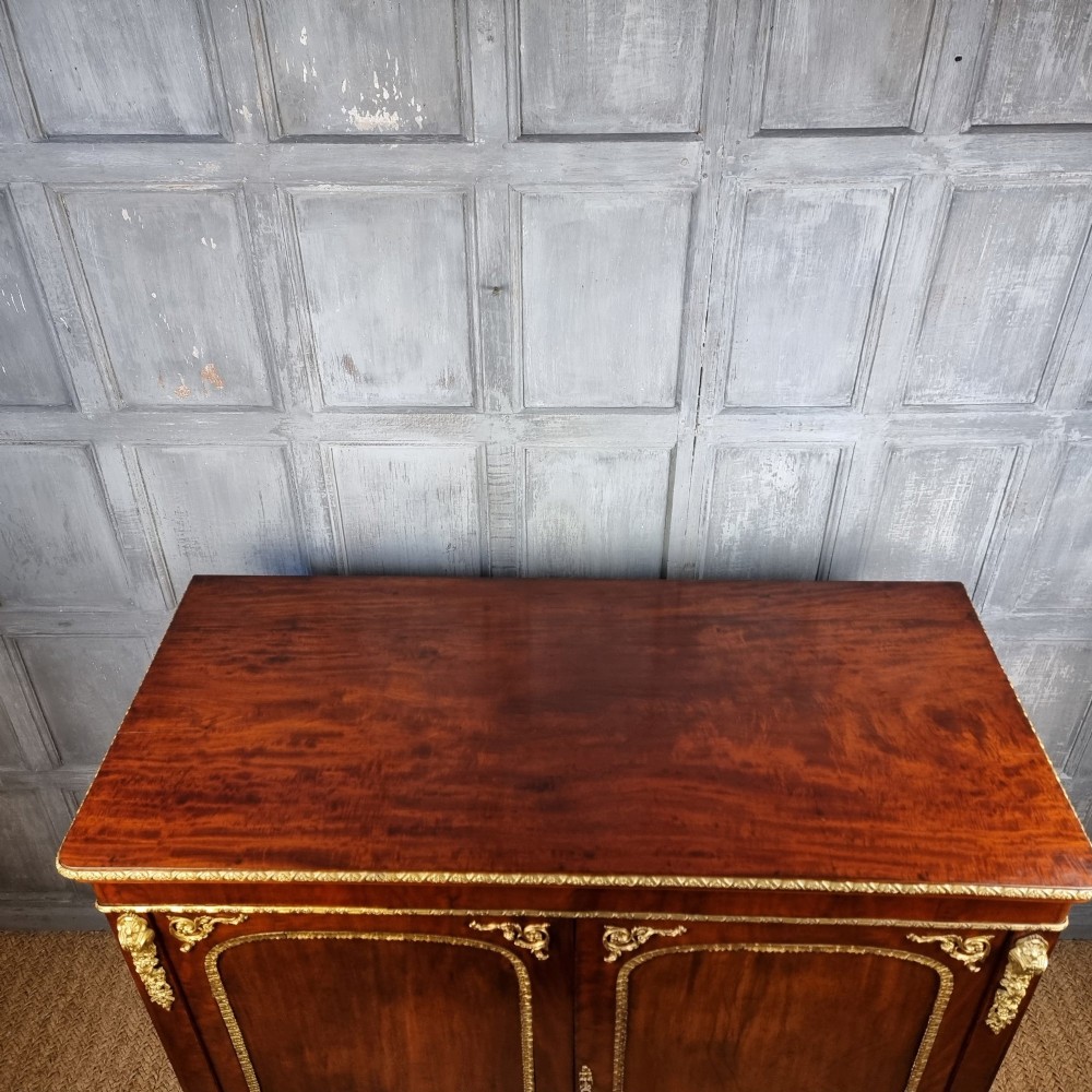 A 19th-century flame mahogany enclosed chest featuring twin doors framed with gilded metal moulding and corner mounts. View VII