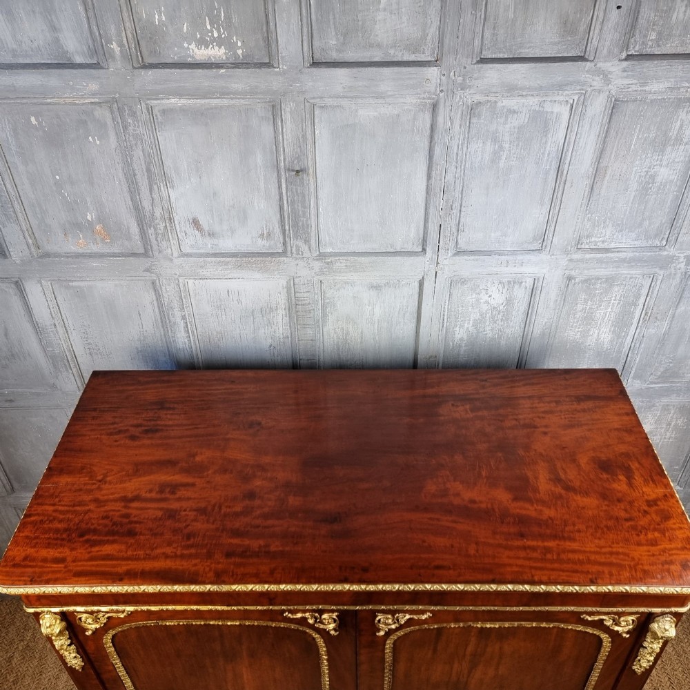 A 19th-century flame mahogany enclosed chest featuring twin doors framed with gilded metal moulding and corner mounts. View VIII