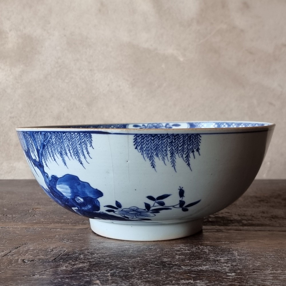 An 18th-century circular Chinese export porcelain punch bowl decorated with hand-painted blue figures under a willow tree. View IV