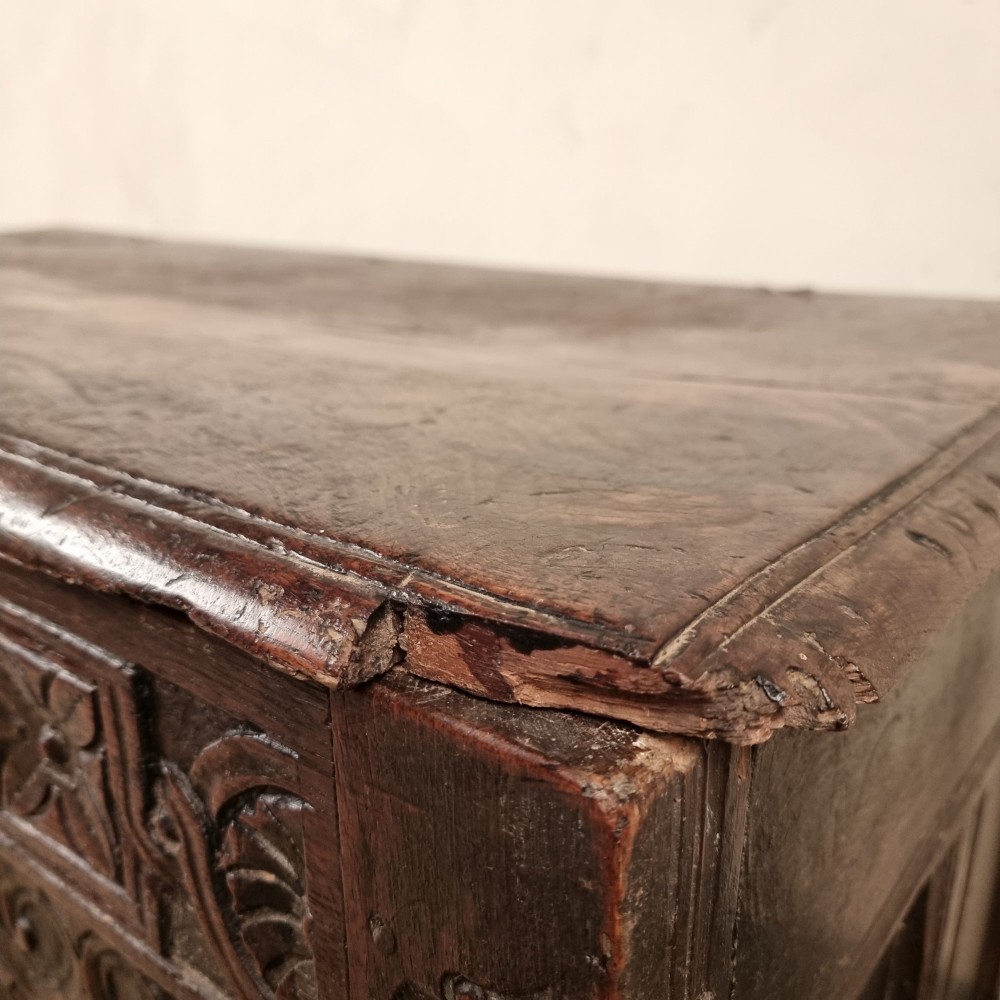 A dark carved oak early 17th-century coffer featuring decorated scrollwork panels and a central iron lockplate. View III