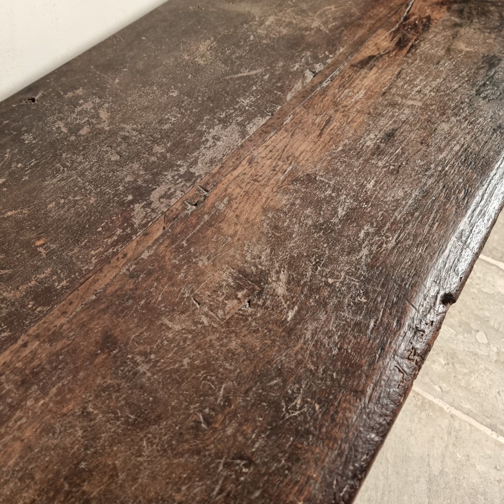 A dark carved oak early 17th-century coffer featuring decorated scrollwork panels and a central iron lockplate. View VI