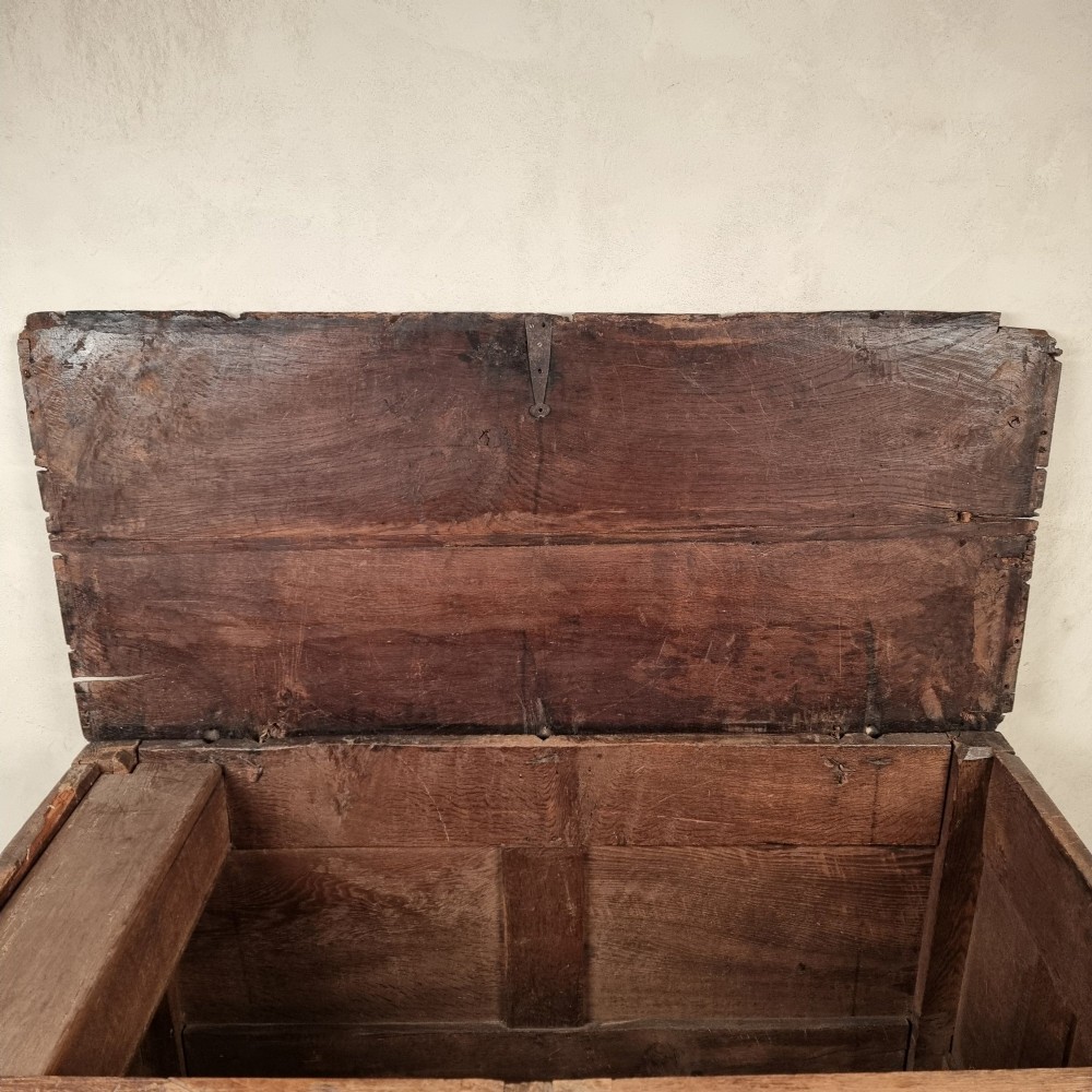 A dark carved oak early 17th-century coffer featuring decorated scrollwork panels and a central iron lockplate. View VIII