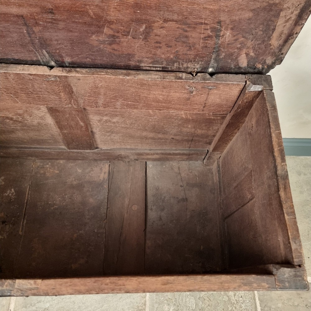 A dark carved oak early 17th-century coffer featuring decorated scrollwork panels and a central iron lockplate. View IX