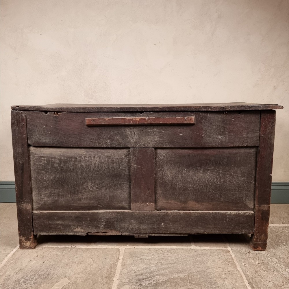 A dark carved oak early 17th-century coffer featuring decorated scrollwork panels and a central iron lockplate. View XIII
