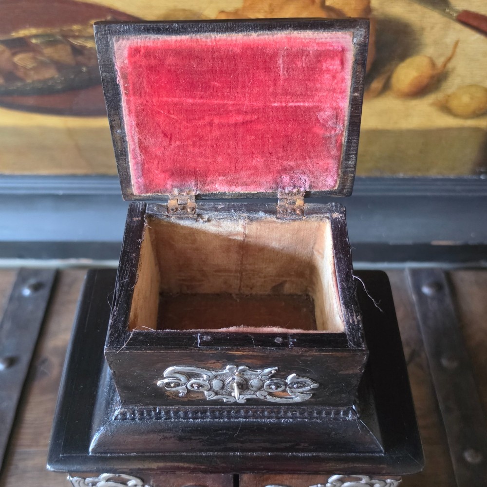 A tiered 18th-century walnut jewellery cabinet featuring ornate silvered metal hinges, a central latch mechanism, a lower drawer, and turned bun feet. View V