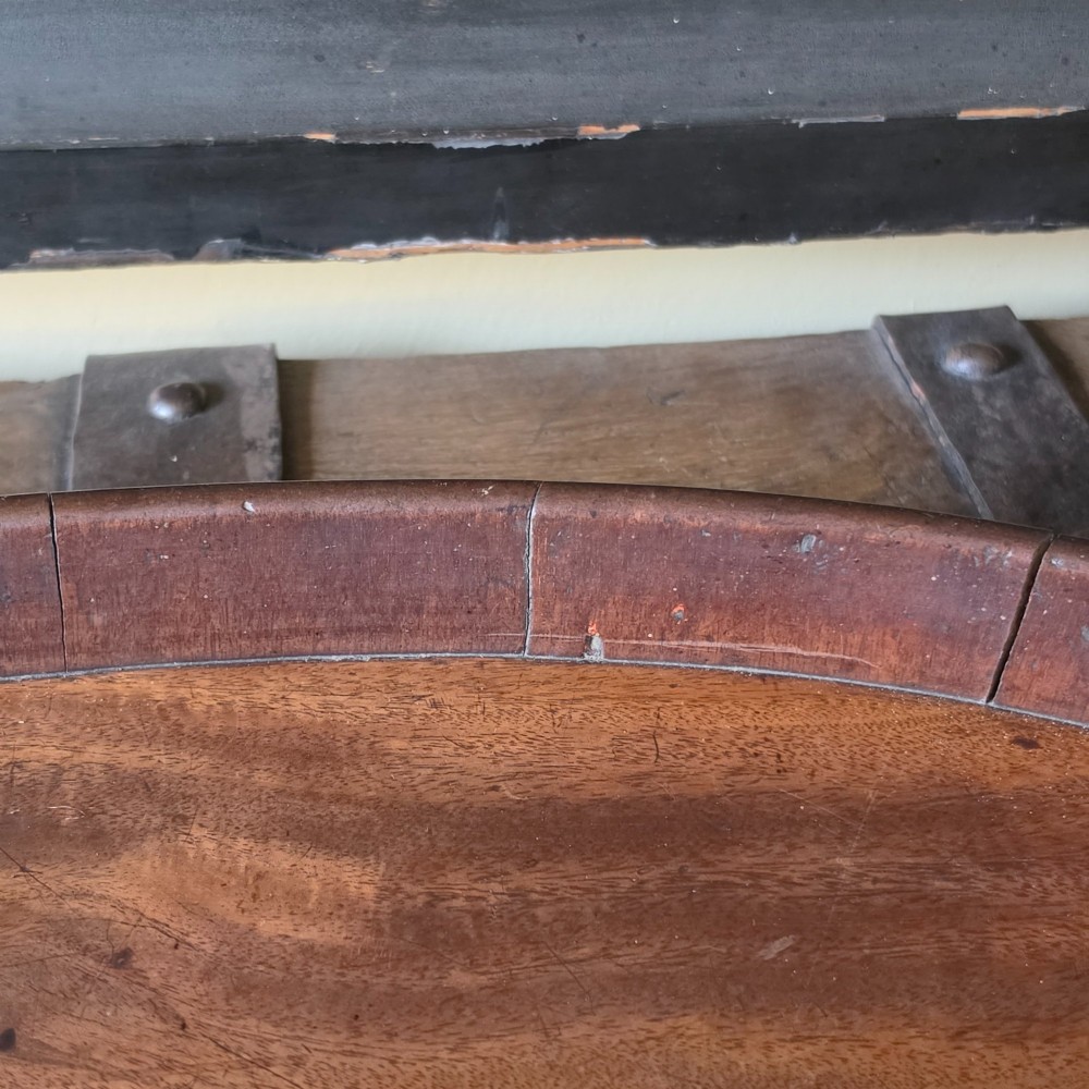 An 18th-century oval mahogany serving tray featuring a raised gallery edge with brass rim binding and carved scroll handles. View VIII