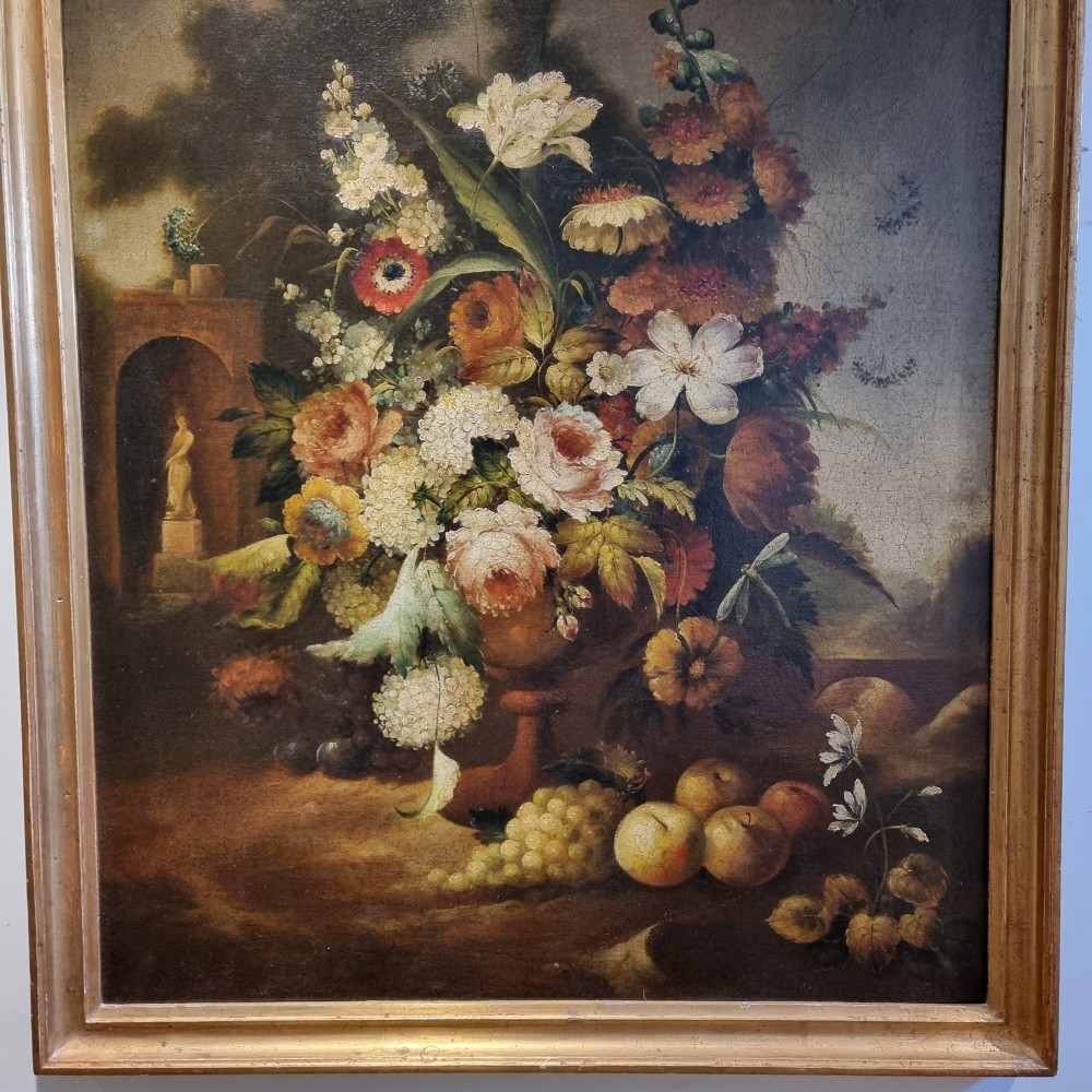 An 18th-century style oil painting on canvas depicting a floral arrangement in an urn with fruit at the base, housed within a gilded wooden frame. View III