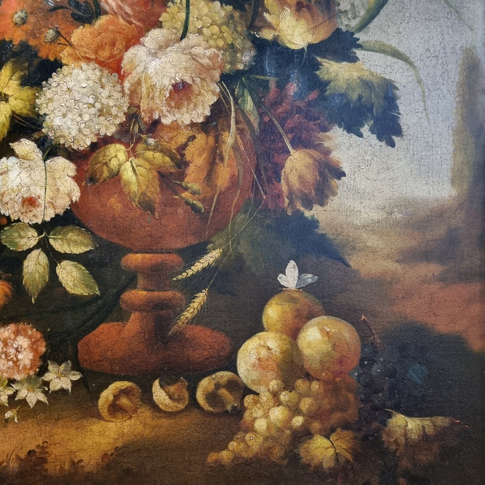 An 18th-century style oil painting on canvas depicting a floral arrangement in an urn with fruit at the base, housed within a gilded wooden frame. View X