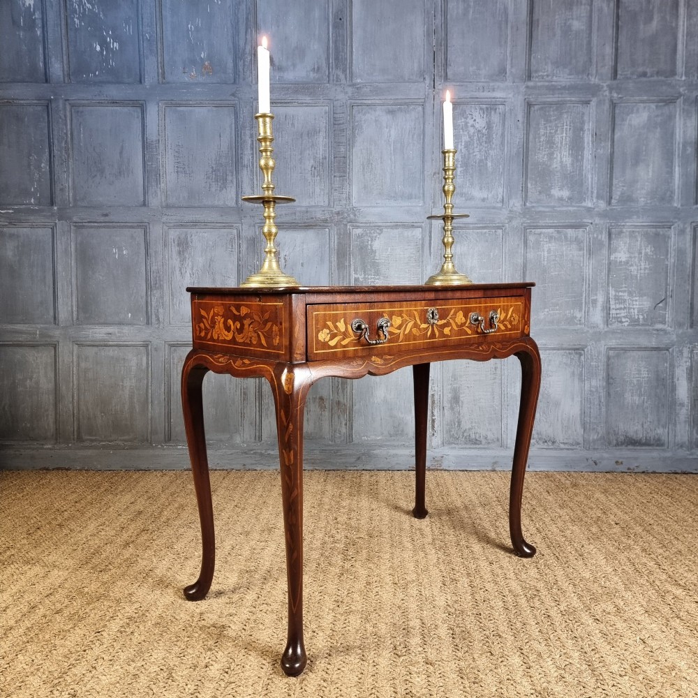 An 18th-century warm brown timber centre table with intricate floral marquetry inlay across the single drawer front, apron, and slender cabriole legs.