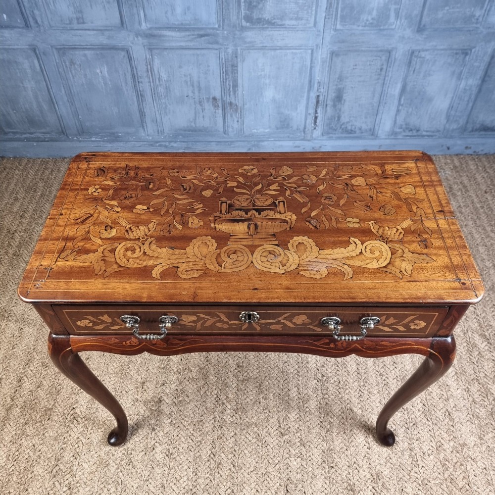An 18th-century warm brown timber centre table with intricate floral marquetry inlay across the single drawer front, apron, and slender cabriole legs. View V