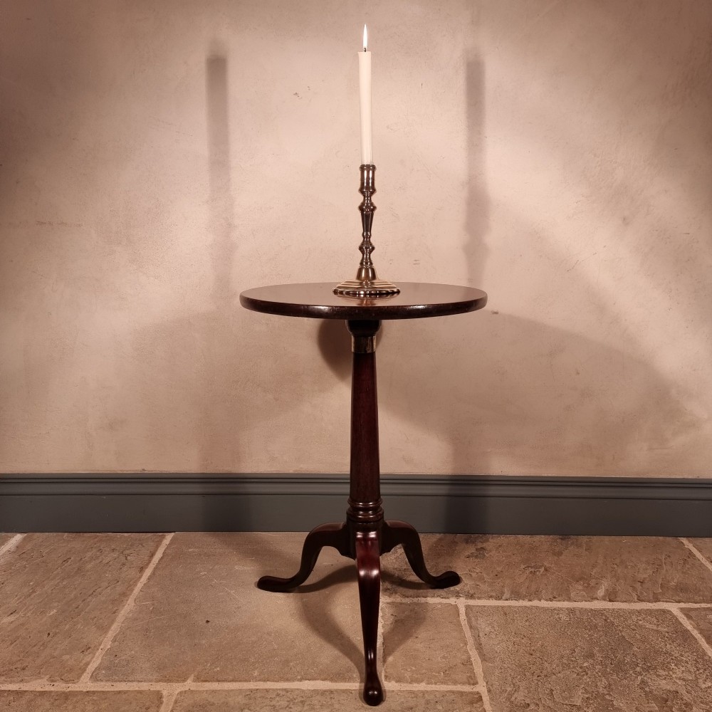 A dark mahogany 18th-century wine table featuring a circular top, turned central pedestal, and three cabriole tripod legs.