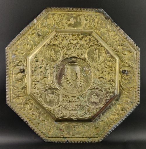 An octagonal nineteenth-century silvered metal charger featuring relief repousse decoration depicting a central portrait bust of Miguel de Cervantes surrounded by narrative vignettes and foliate scrollwork. View VI