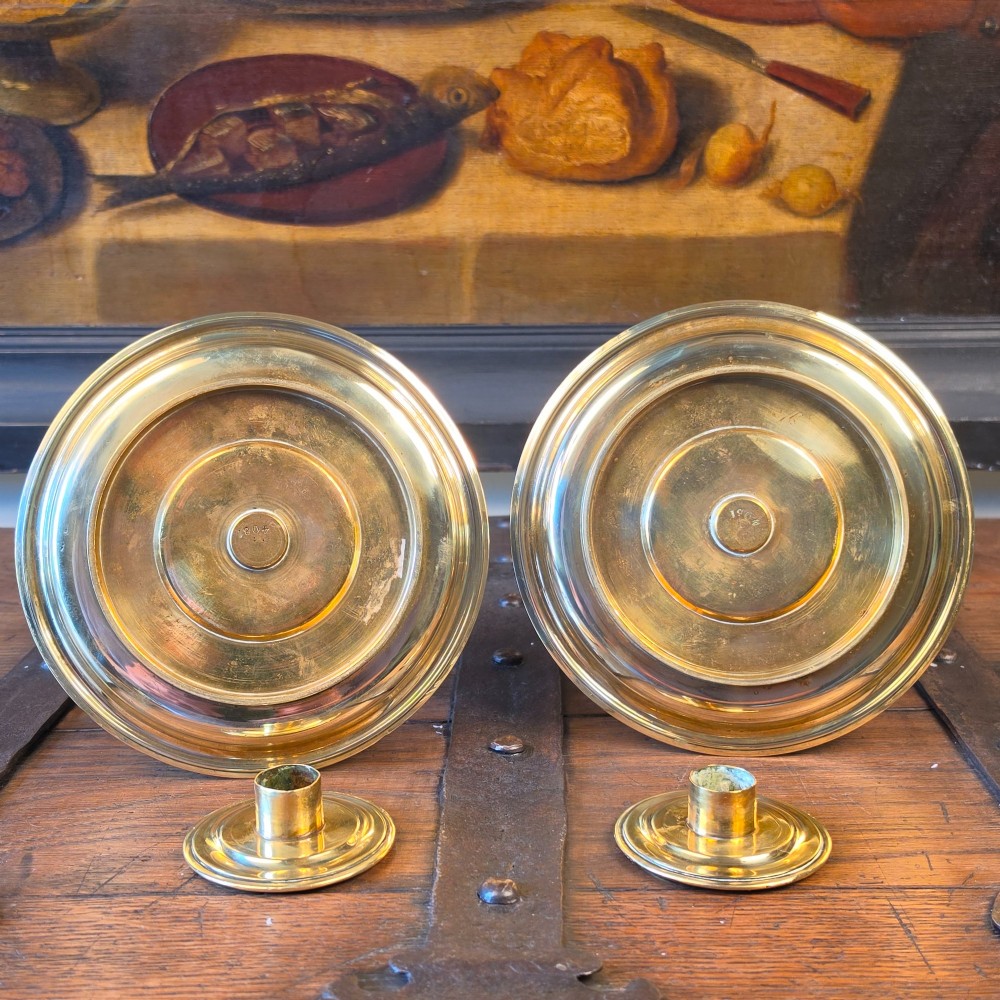 A pair of 19th-century turned brass candlesticks featuring wide circular drip pans and stepped bases. View V