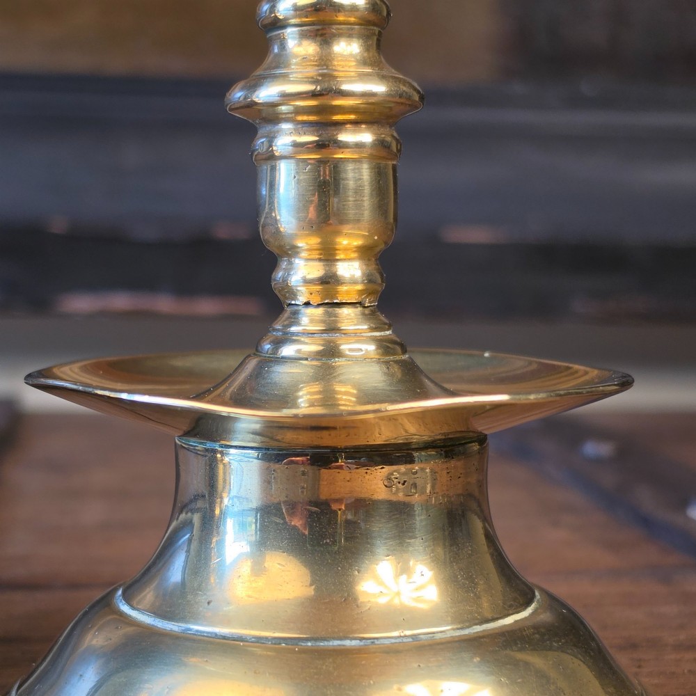 A pair of small turned brass candlesticks featuring flared circular bases, baluster stems, and sockets with wax removal holes. View III