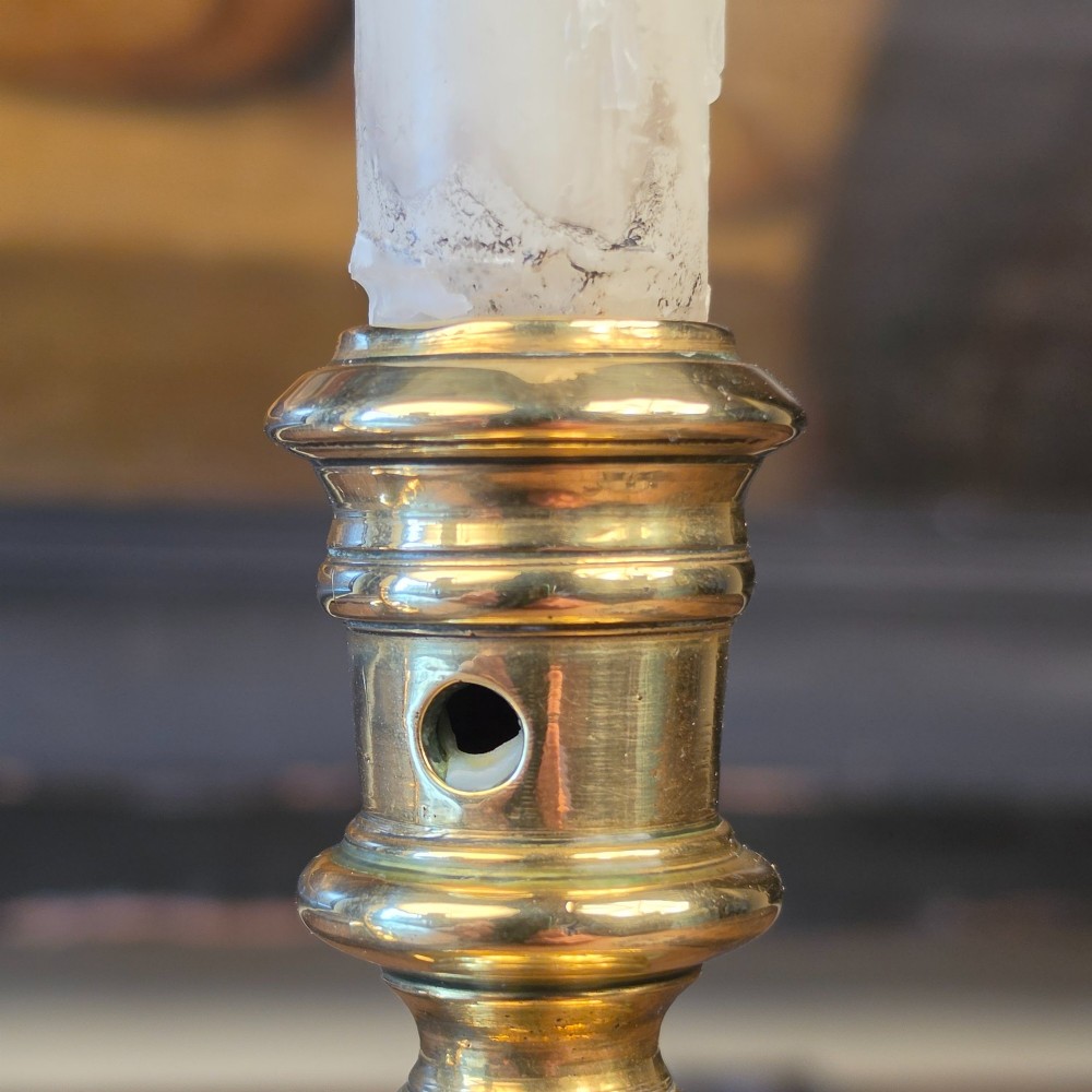A pair of small turned brass candlesticks featuring flared circular bases, baluster stems, and sockets with wax removal holes. View VI