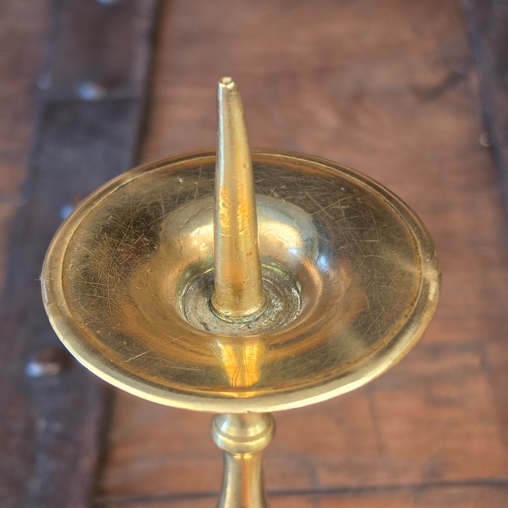 A pair of turned brass pricket candlesticks with circular drip pans and central sharp spikes on stepped round bases. View II