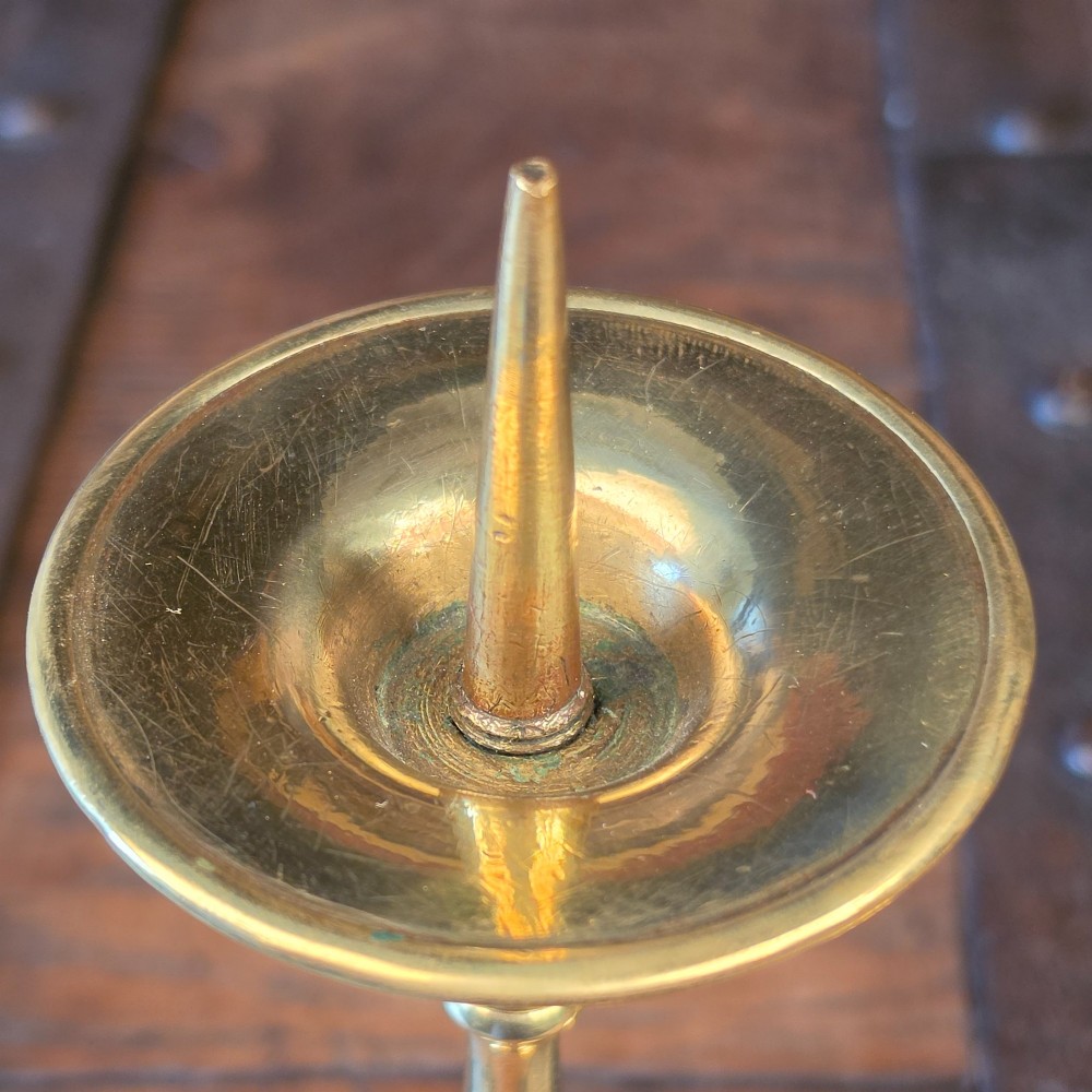 A pair of turned brass pricket candlesticks with circular drip pans and central sharp spikes on stepped round bases. View III
